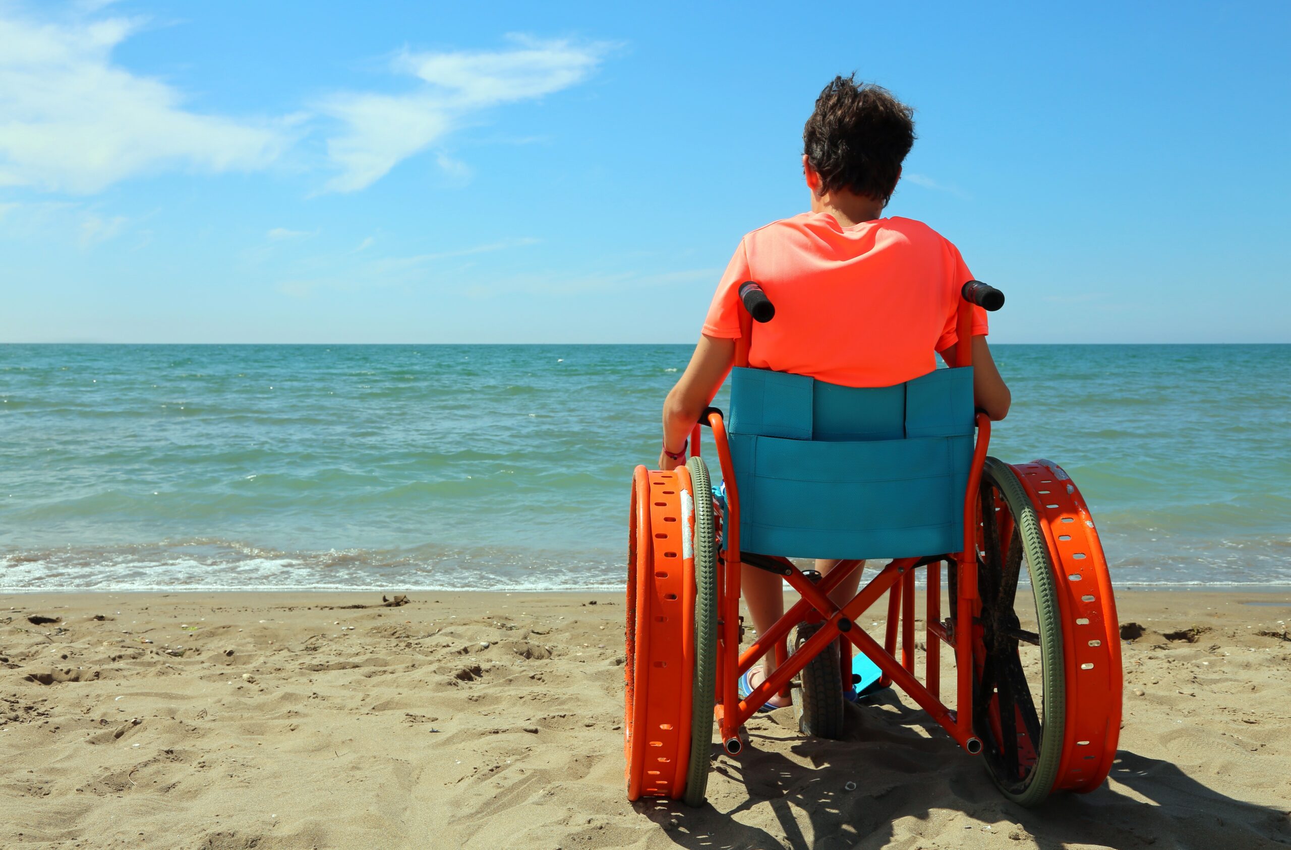 Young boy on the wheelchair by the sea Turismo accessibile